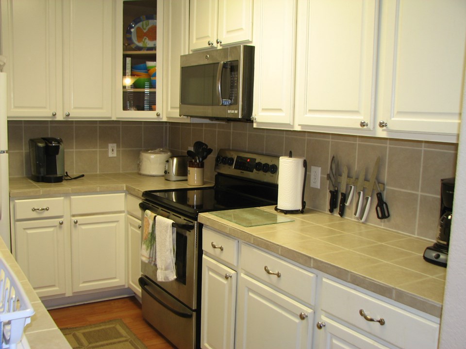 tile countertops, laminate flooring throughout, built-in microwave, custom cabinets