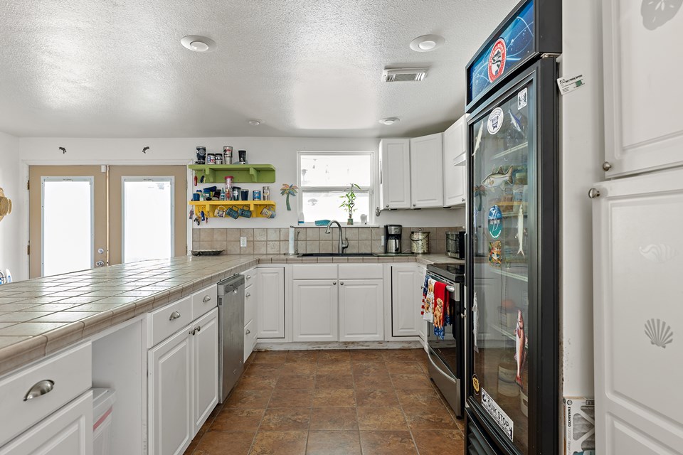beautiful kitchen with breakfast bar and a propane stove the double doors to your left in the background lead to the backyard covered patio and pool area.