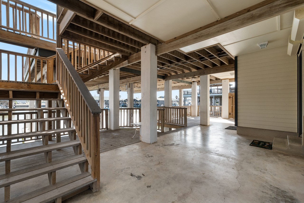 patio under the main home with a great view of the harbor to the right of the photo is the enclosed garage and you can see the steps leading to the downstairs guest house